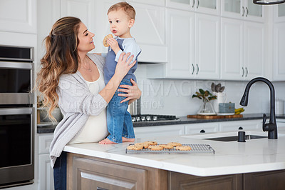 Buy stock photo Shot of a pregnant woman and her son spending time together in the kitchen at home