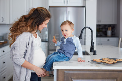Buy stock photo Shot of a pregnant woman baking while spending spending time with her toddler son at home