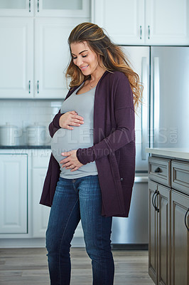 Buy stock photo Cropped shot of an attractive young pregnant woman standing in her kitchen at home