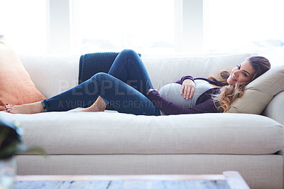 Buy stock photo Full length shot of an attractive young pregnant woman lying down on the sofa at home
