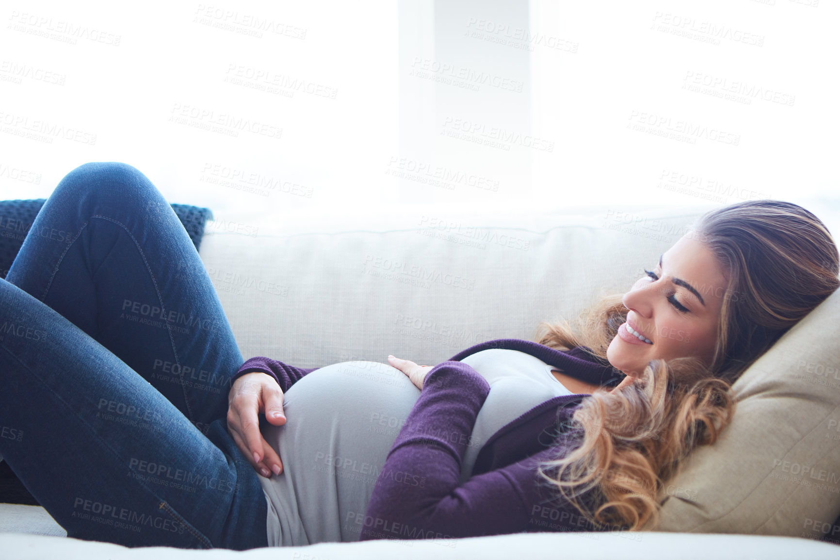 Buy stock photo Cropped shot of an attractive young pregnant woman taking a nap on the sofa at home