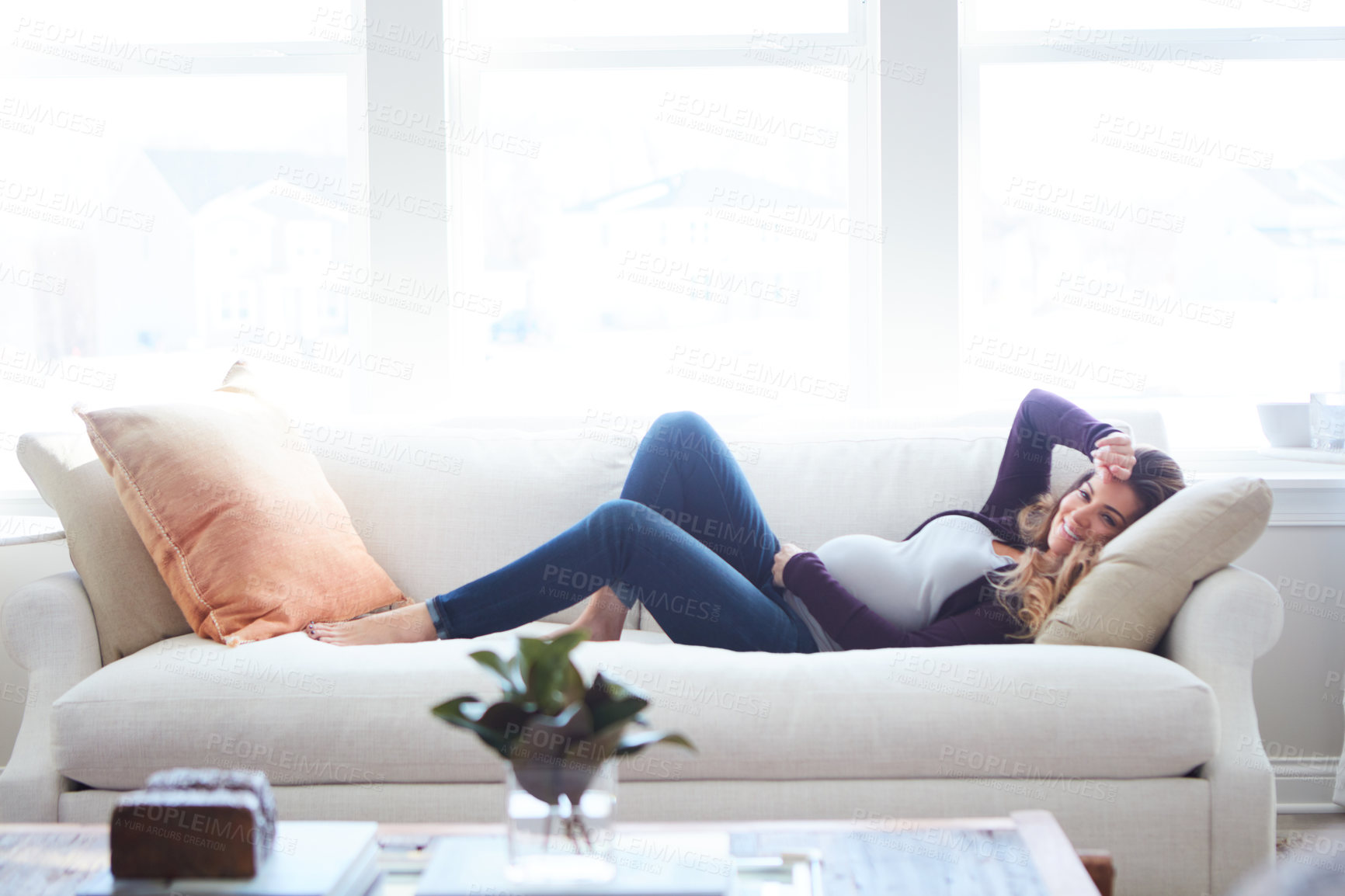 Buy stock photo Full length shot of an attractive young pregnant woman lying down on the sofa at home