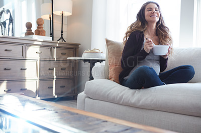 Buy stock photo Full length shot of an attractive young pregnant woman eating breakfast while sitting on the sofa at home