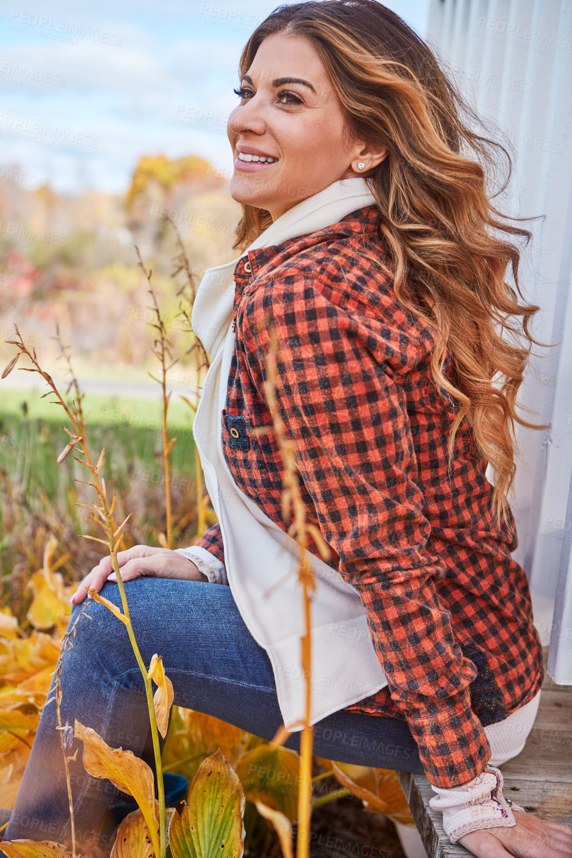 Buy stock photo Cropped shot of an attractive young woman sitting on the ledge of a gazebo in the park during autumn