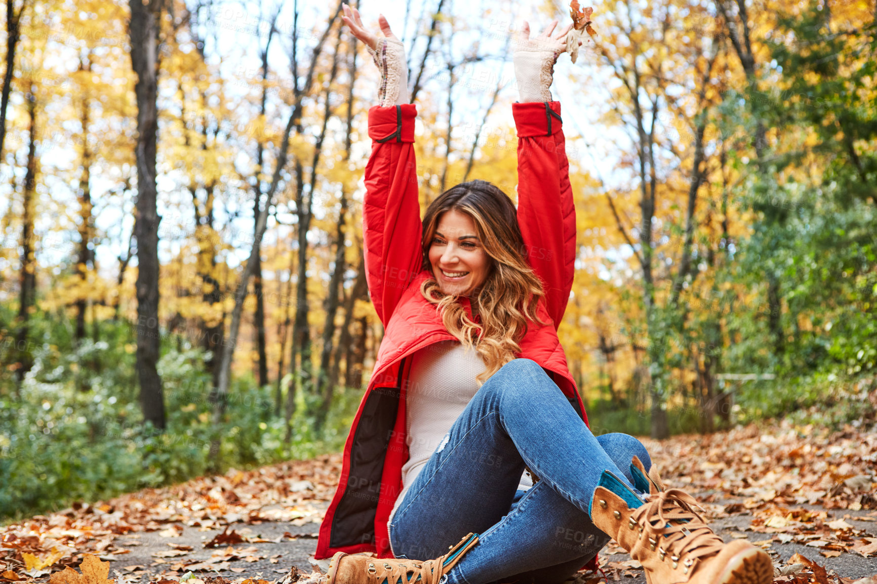 Buy stock photo Cropped shot of an attractive young woman throwing leaves while sitting in the forest during autumn
