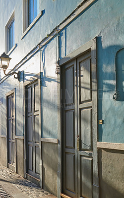 Buy stock photo Classic architecture of vibrant buildings with blue doors in a city. Closeup view of ancient and traditional homes or houses in a small vintage town or village with bright colors and a unique design