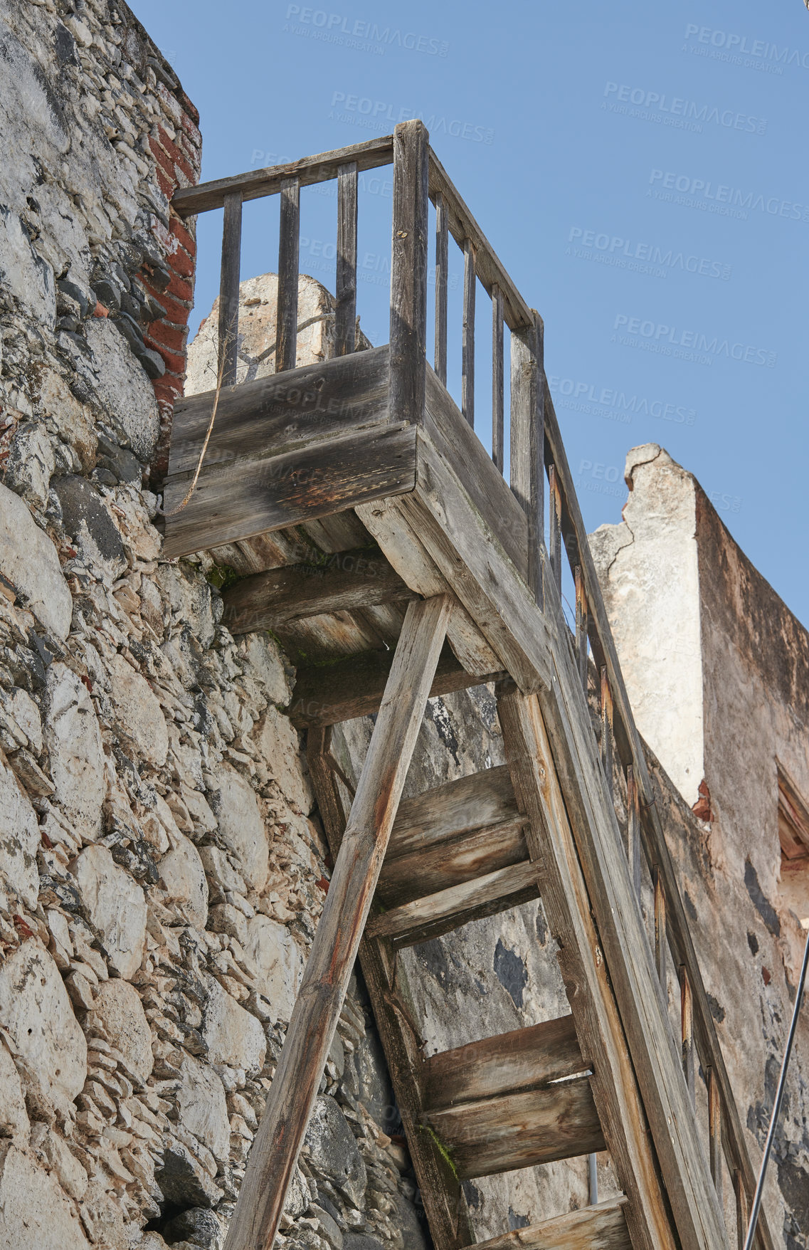 Buy stock photo Old wooden stairs leading up to a rooftop of a historic building against a blue sky background. Weathered staircase    and a vintage stone wall background. Spot to watch the view and get fresh air