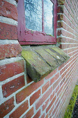 Buy stock photo Old dirty window on a brick wall house or home. Ancient casement with red wood frame on a historic building with a clumpy paint texture. Exterior details of a windowsill in a traditional country town