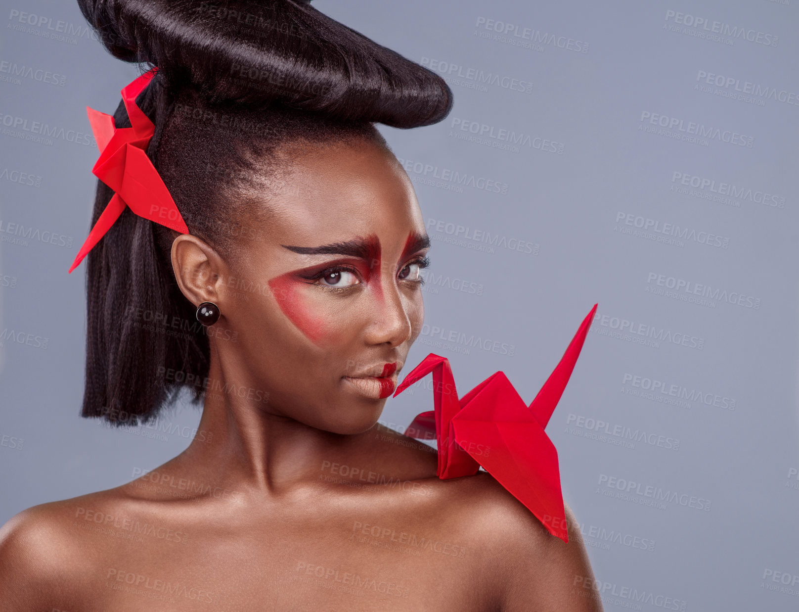 Buy stock photo Portrait, cosmetics and black woman with origami for beauty in studio isolated on gray background. Face, creative makeup and confident serious model with red paper crane in hair, skincare and art