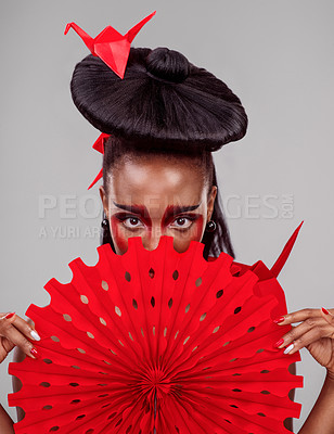 Buy stock photo Studio shot of a beautiful young woman wearing Asian inspired makeup and posing with a fan against a grey background