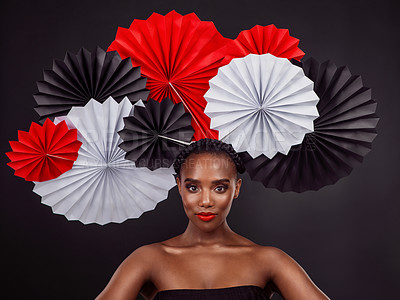 Buy stock photo Face, makeup and black woman with origami fans in studio isolated on a dark background. Serious portrait, beauty cosmetics and skincare of female model with traditional Japanese paper art for culture