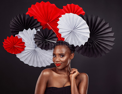 Buy stock photo Portrait, skincare and black woman with origami fans in studio isolated on a dark background. Face, makeup cosmetics and beauty of African female model with traditional Japanese paper hat for fashion