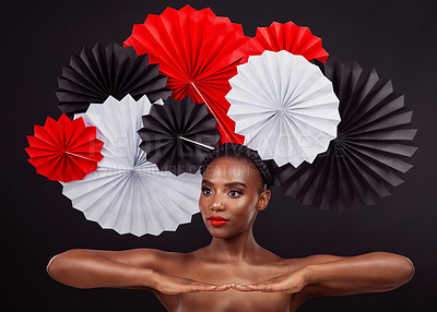 Buy stock photo Studio shot of a beautiful young woman posing with a origami fans against a black background