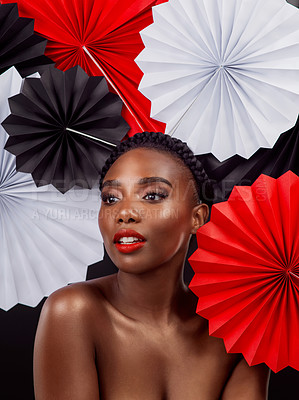 Buy stock photo Craft, thinking and black woman with origami fans in studio, beauty and dark background. Face, makeup and cosmetics of female model with pride, traditional Japanese and paper art for culture hat