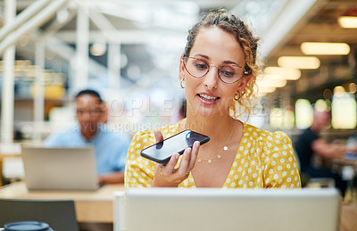 Buy stock photo Shot of a young businesswoman using a laptop and smartphone in a modern office