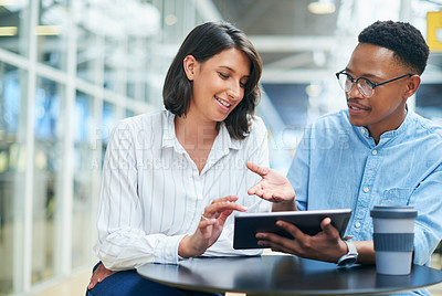 Buy stock photo Shot of a young businessman and businesswoman using a digital tablet in a modern office