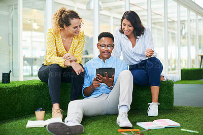 Buy stock photo Shot of a group of young businesspeople using a digital tablet in a modern office