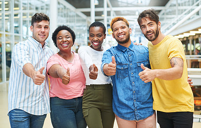 Buy stock photo Portrait of a group of young businesspeople showing thumbs in a modern office