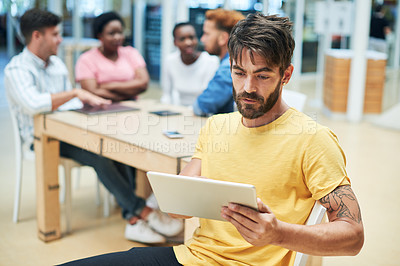 Buy stock photo Shot of a young businessman using a digital tablet during a team meeting in a modern office