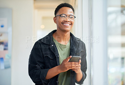 Buy stock photo Shot of a young businessman using a smartphone in a modern office