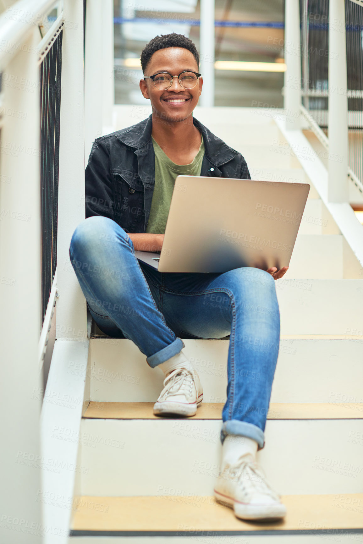 Buy stock photo Shot of a young businessman using a laptop on the stairs of a modern office