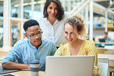 Buy stock photo Shot of a group of young businesspeople using a laptop in a modern office