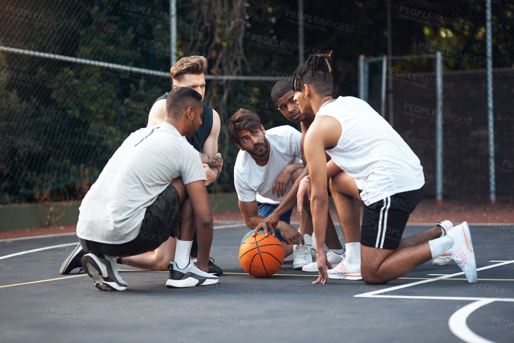 Buy stock photo Shot of a group of sporty young men chatting to each other on a basketball court