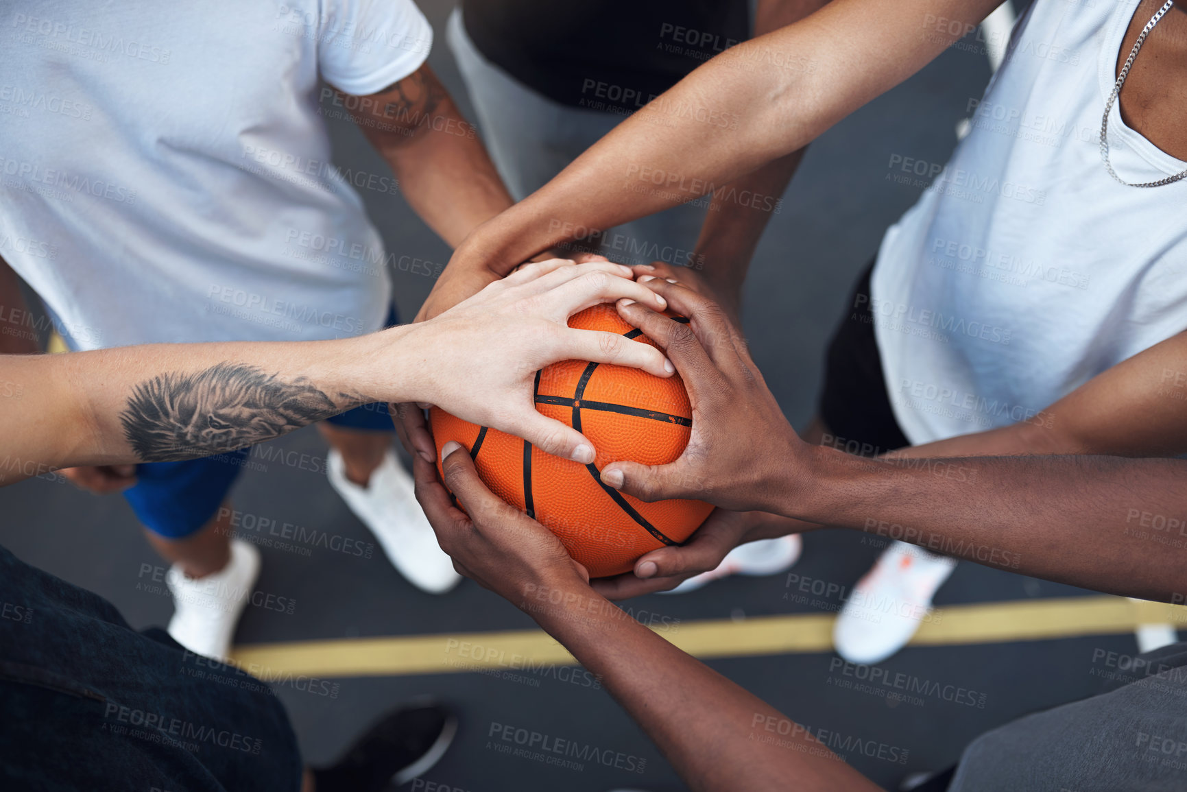 Buy stock photo Closeup shot of a group of sporty young men huddled around a basketball on a sports court