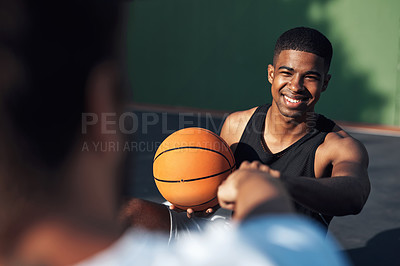 Buy stock photo Shot of a sporty young man giving his teammate a fist bump on a basketball court