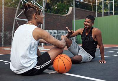 Buy stock photo Shot of two sporty young men chatting to each other on a basketball court