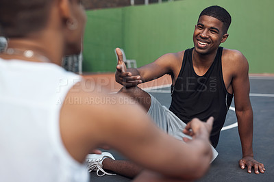 Buy stock photo Shot of two sporty young men chatting to each other on a basketball court