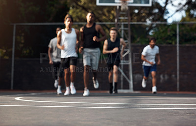 Buy stock photo Defocused shot of a group of sporty young men running on a sports court