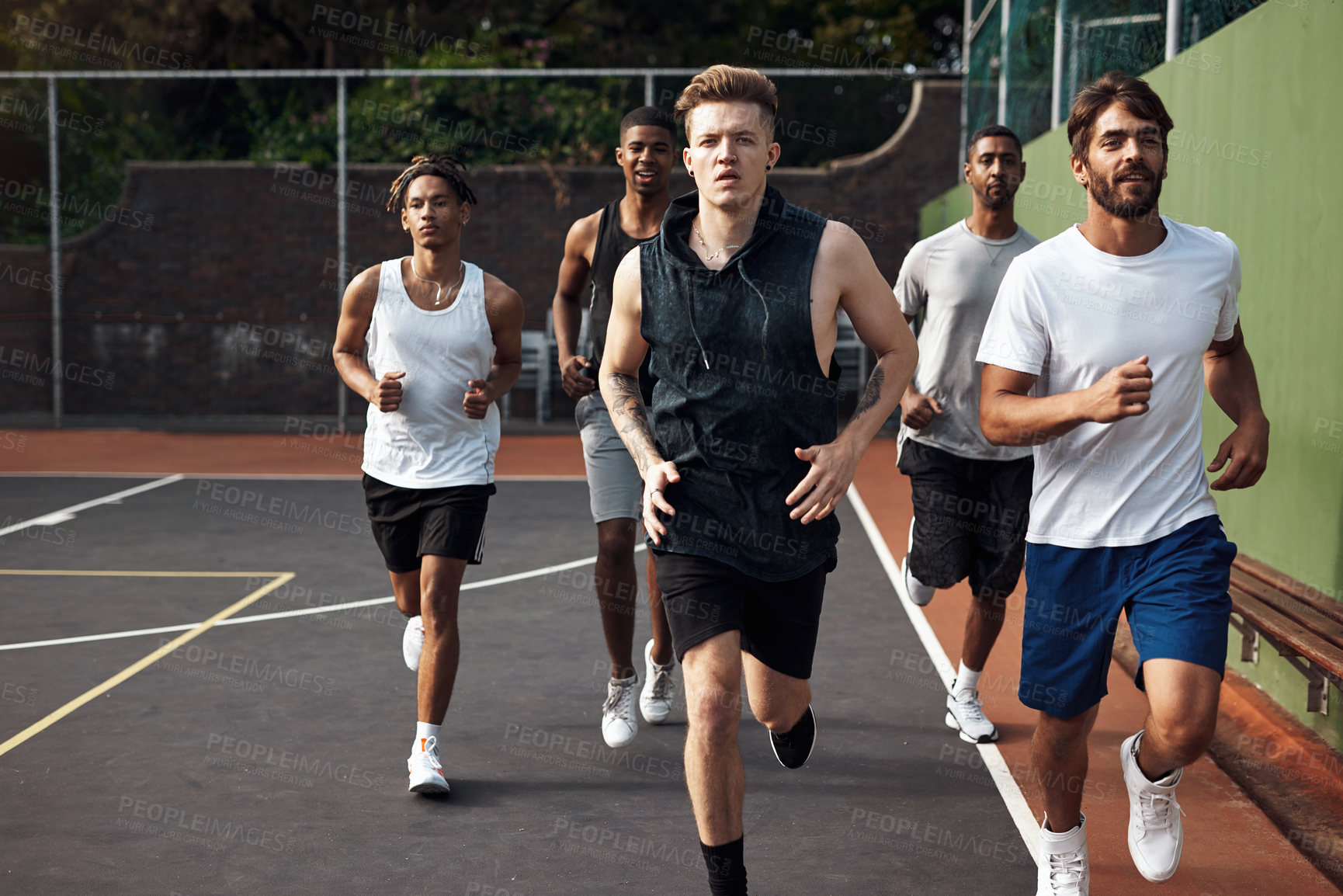 Buy stock photo Shot of a group of sporty young men running on a sports court