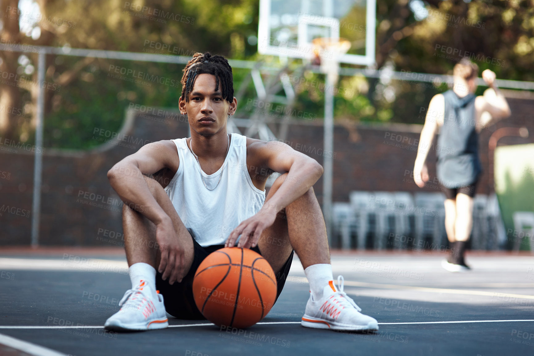 Buy stock photo Portrait of a sporty young man sitting on a basketball court