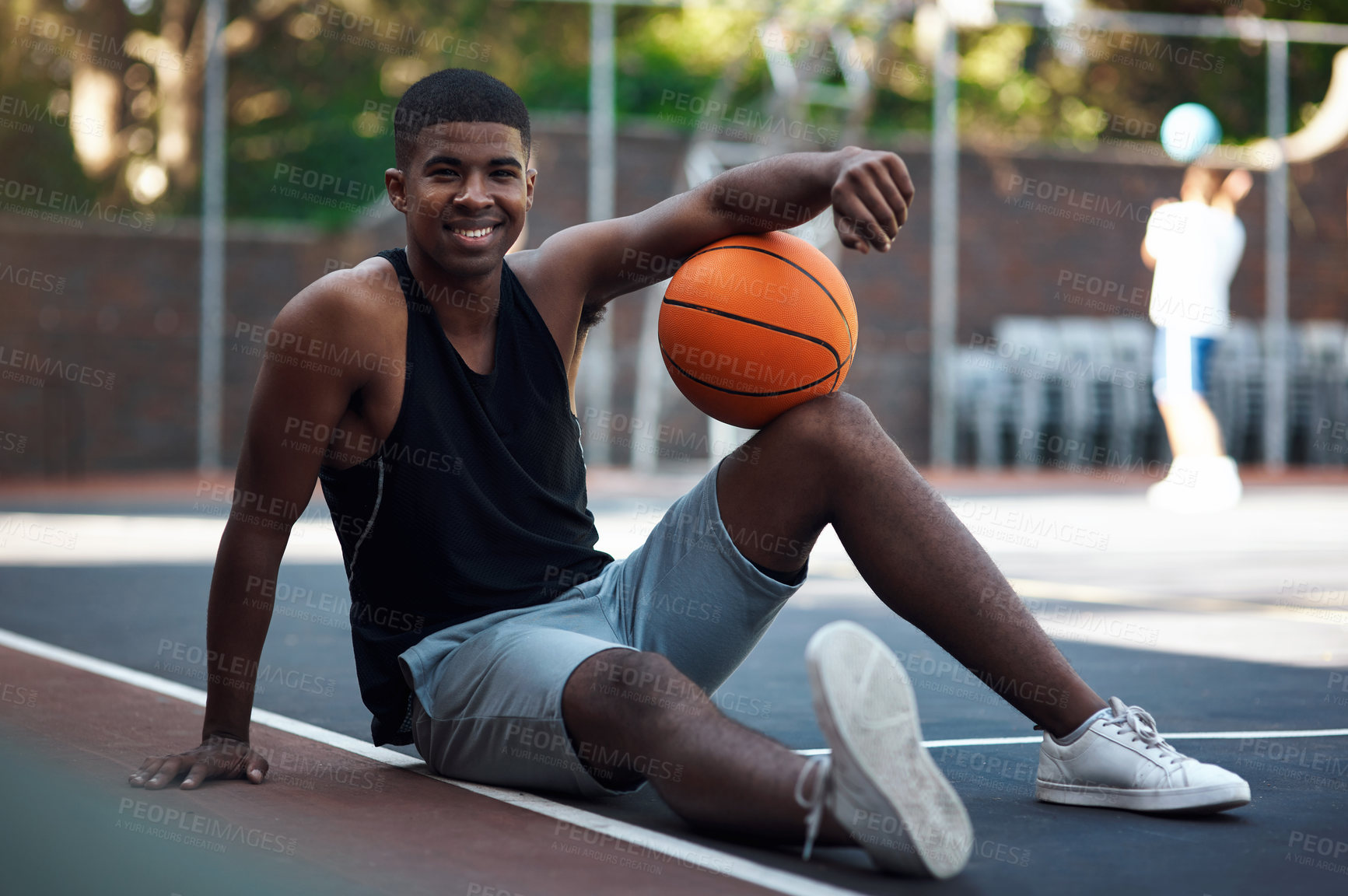 Buy stock photo Portrait of a sporty young man stretching his legs on a basketball court