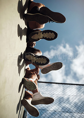 Buy stock photo Closeup shot of a group of sporty young men sitting on a wall on a sports court