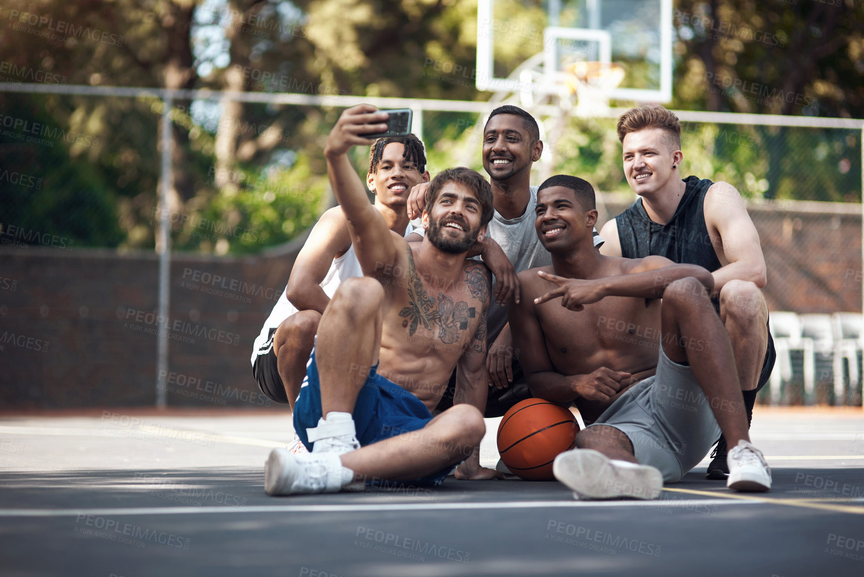 Buy stock photo Shot of a group of sporty young people taking selfies together on a sports court