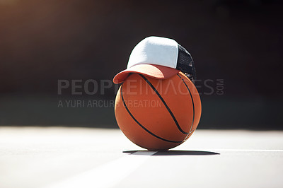 Buy stock photo Still life shot of a hat placed on top of a basketball in a sports court