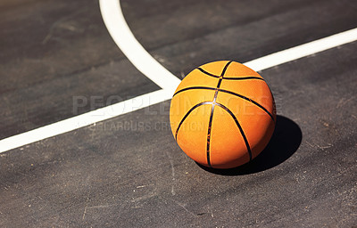 Buy stock photo Still life shot of a basketball on the ground in a sports court