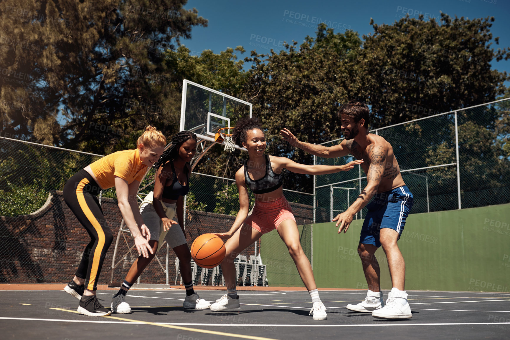 Buy stock photo Shot of a group of sporty young people playing basketball on a sports court