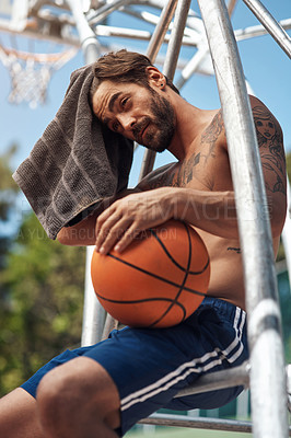 Buy stock photo Shot of a sporty young man taking a break on a sports court