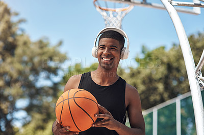 Buy stock photo Shot of a sporty young man listening to music while playing basketball on a sports court