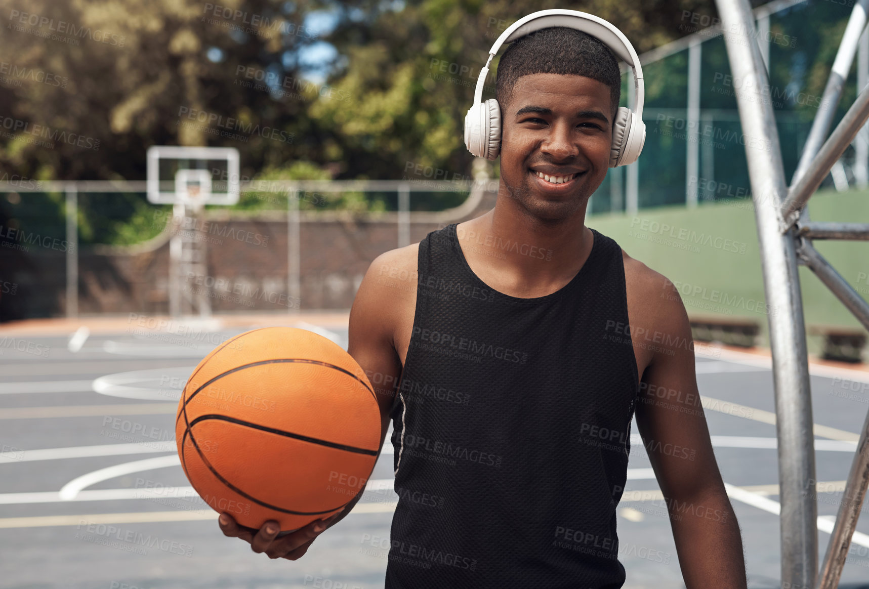 Buy stock photo Portrait of a sporty young man listening to music while playing basketball on a sports court