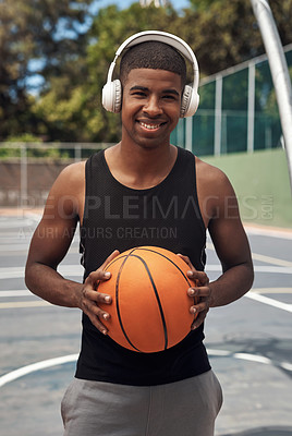 Buy stock photo Portrait of a sporty young man listening to music while playing basketball on a sports court