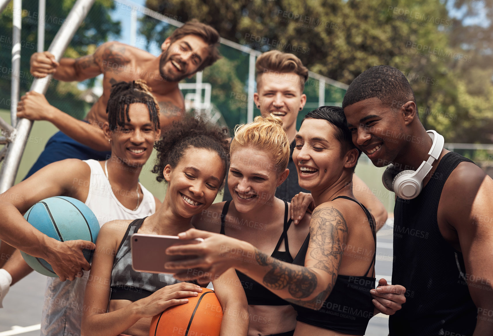 Buy stock photo Shot of a group of sporty young people taking selfies together on a sports court