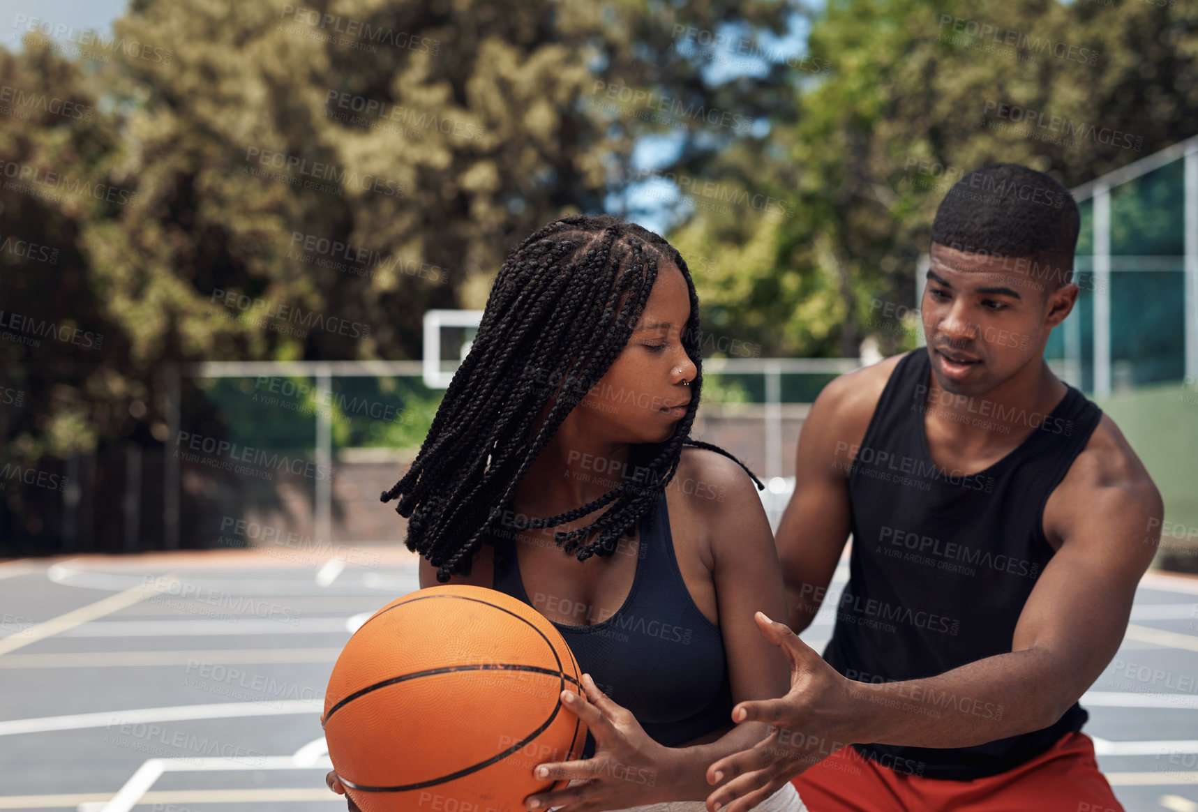 Buy stock photo Shot of two sporty young people playing basketball on a sports court