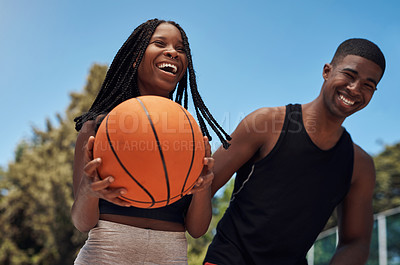 Buy stock photo Shot of two sporty young people playing basketball on a sports court