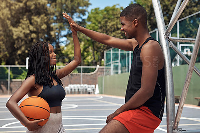 Buy stock photo Shot of a sporty young woman giving her teammate a high five on a basketball court