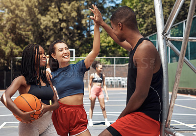 Buy stock photo Shot of a sporty young woman giving her teammate a high five on a basketball court