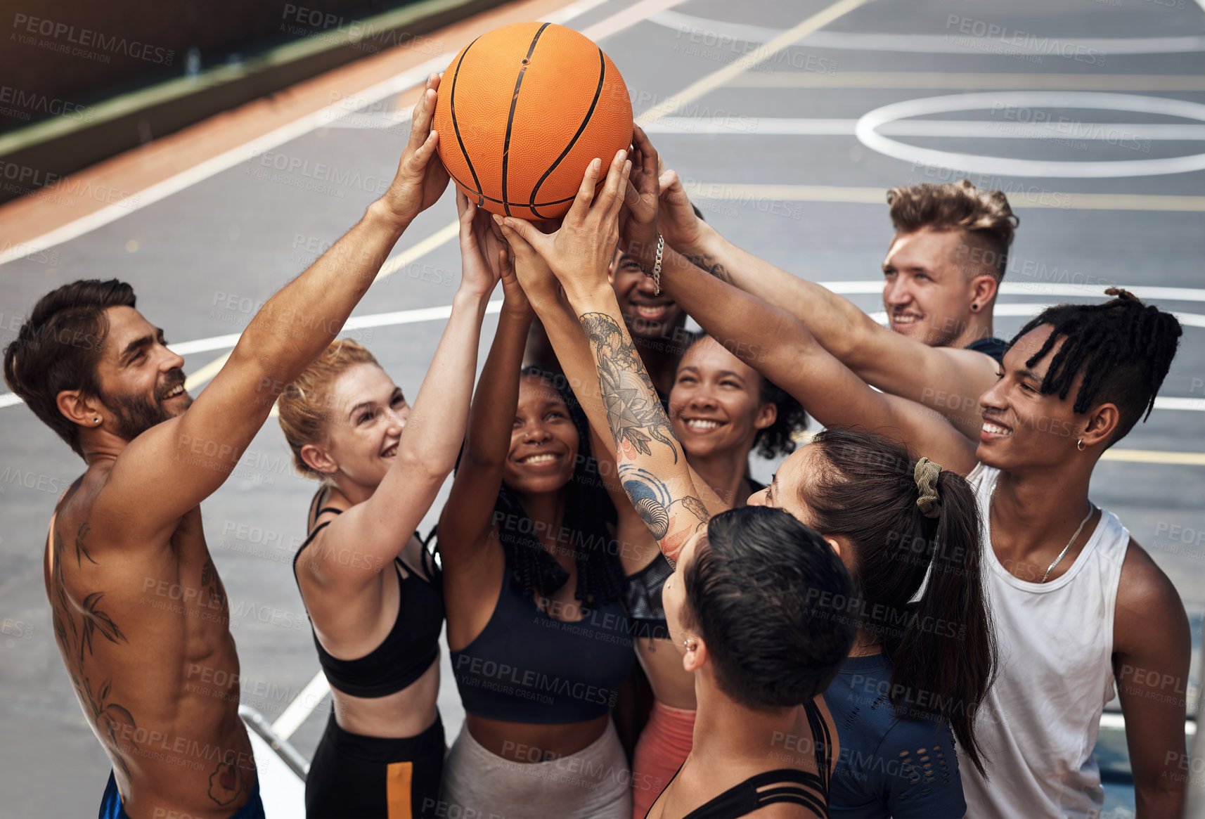 Buy stock photo Shot of a group of sporty young people standing together in a huddle around a basketball on a sports court